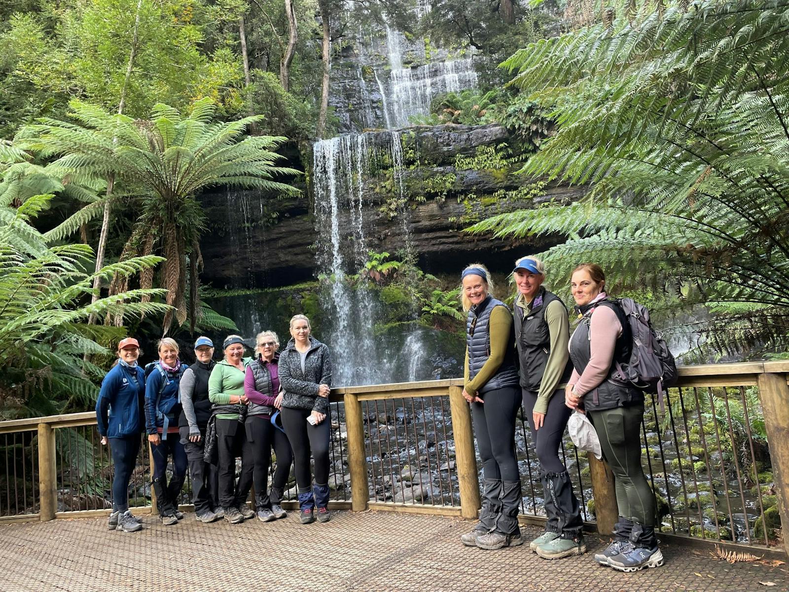 Group smiling at waterfall in Tasmania Heartland
