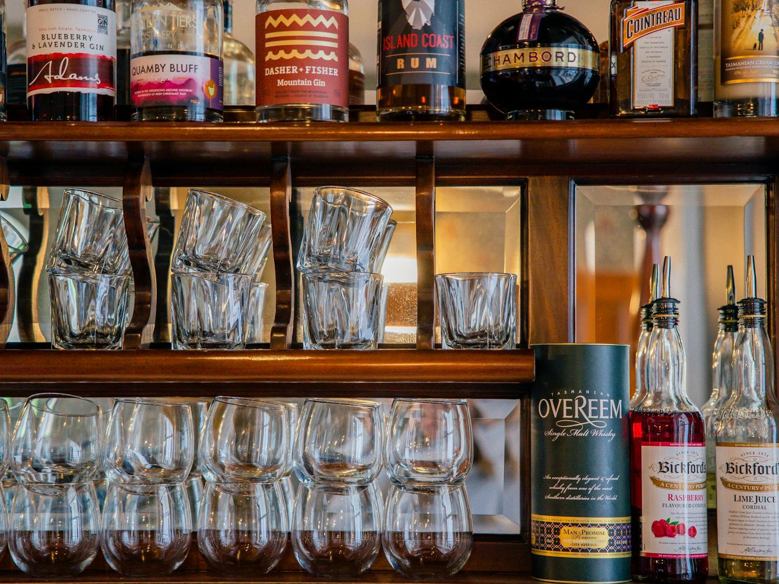 Close up of wooden shelves filled with glassware and alcohol