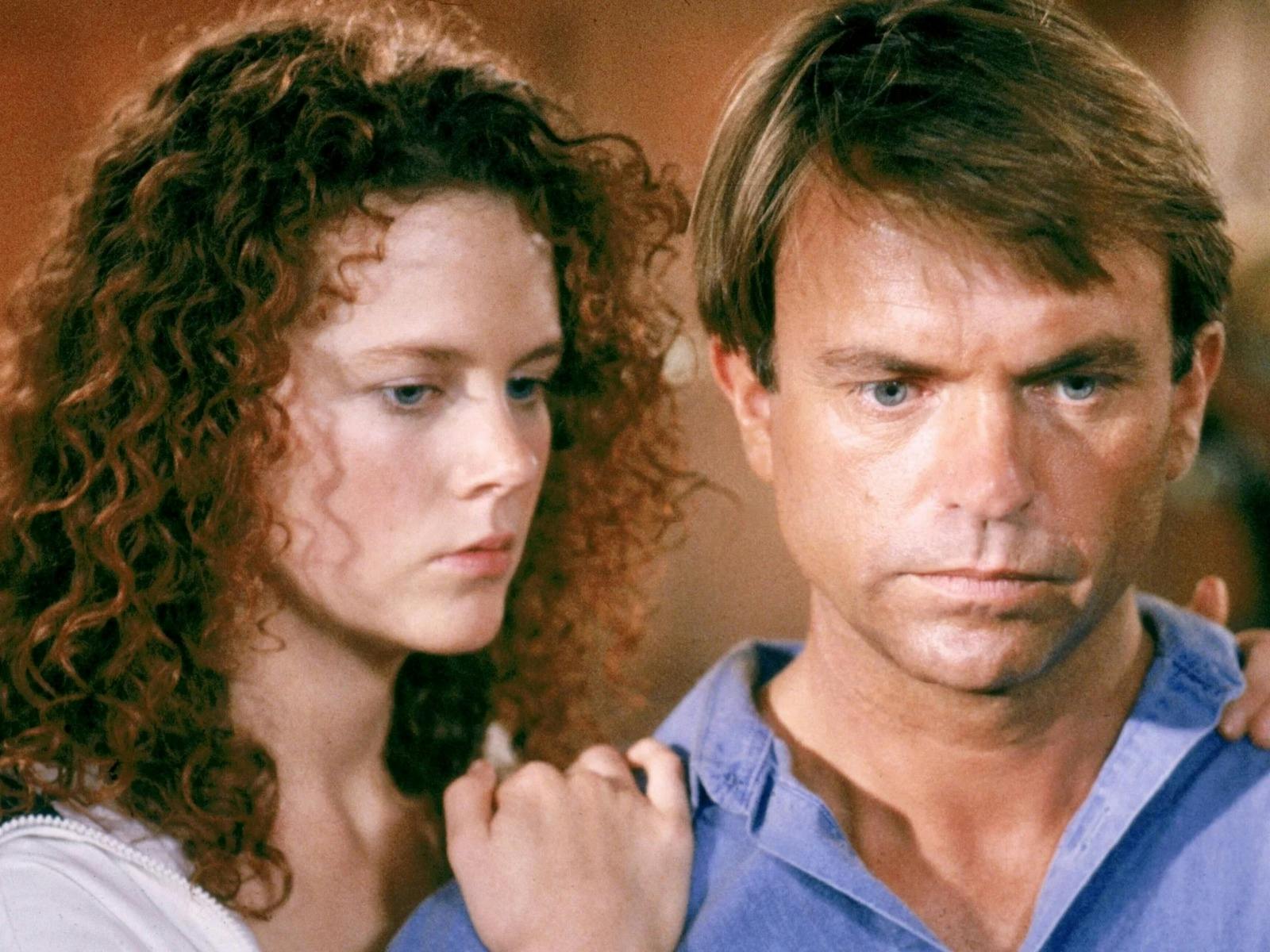 Woman leaning on mans shoulder both looking forlorn