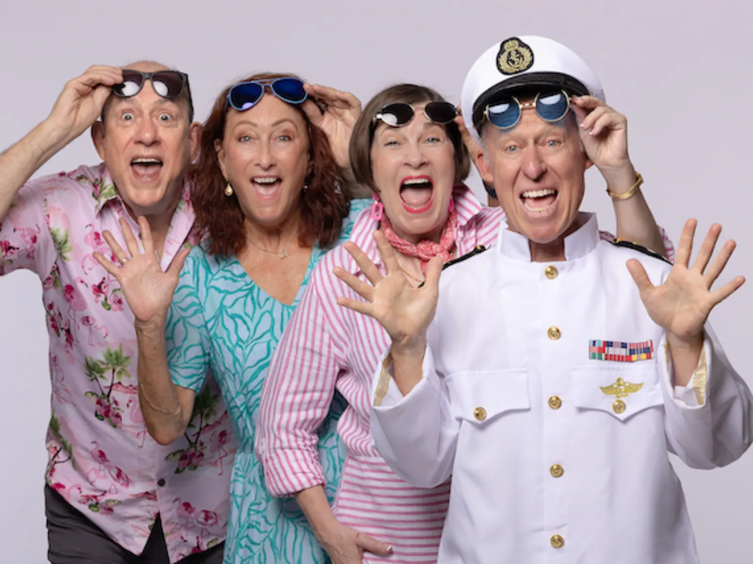 Four senior actors dressing like ship crew and customer on a cruise ship waving at the camera.