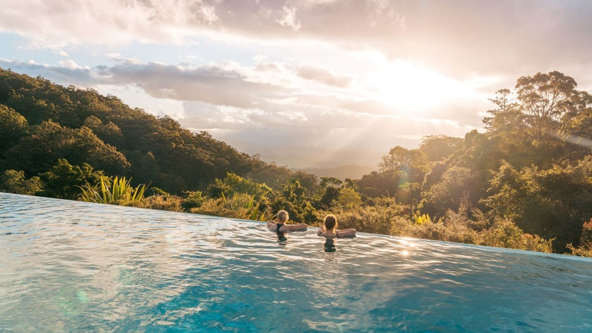 Two adults view the forested valleys below the infinity pool at O'Reilly's Rainforest Retreat Two adults view the forested valleys below the infinity pool at O'Reilly's Rainforest Retreat