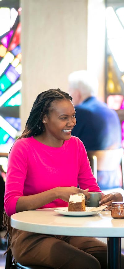 Two young women in a brightly lit cafe, sitting at a white table.