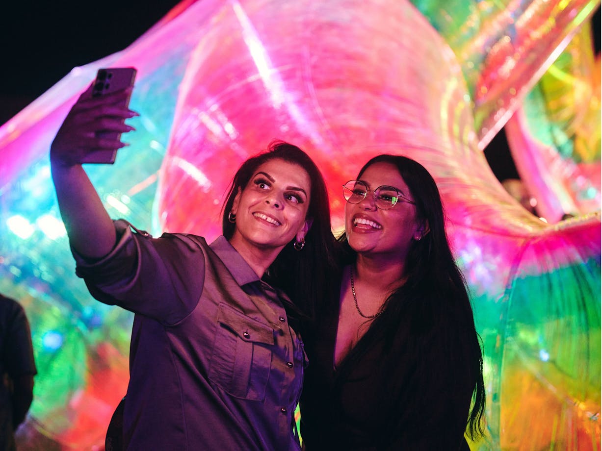 Two females capturing a selfie in front of an Enlighten installation