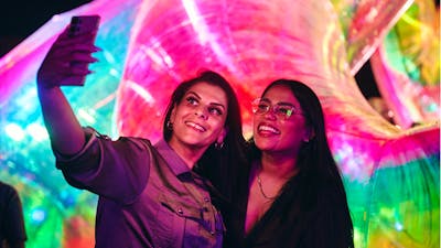 Two females capturing a selfie in front of an Enlighten installation