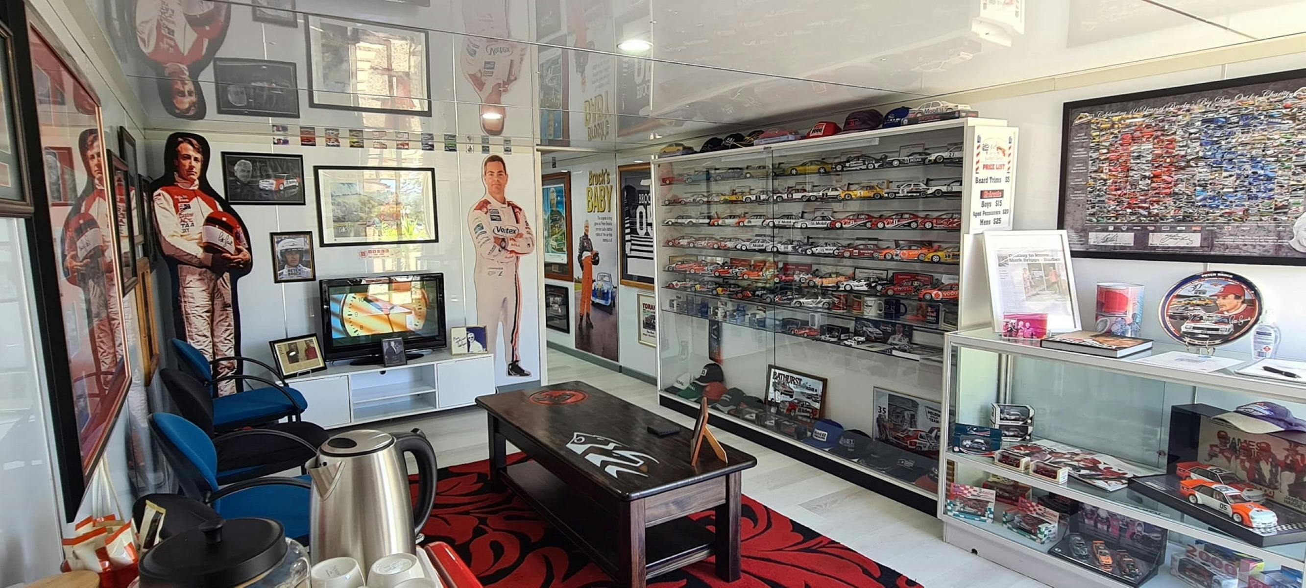 博物館の内部。ガラスの棚には小さな車のレプリカ、本、帽子、額縁がいっぱいに並んでいます。