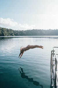 A woman in an arch dive into the crater Lake Eacham from a dock in Tropical North Queensland