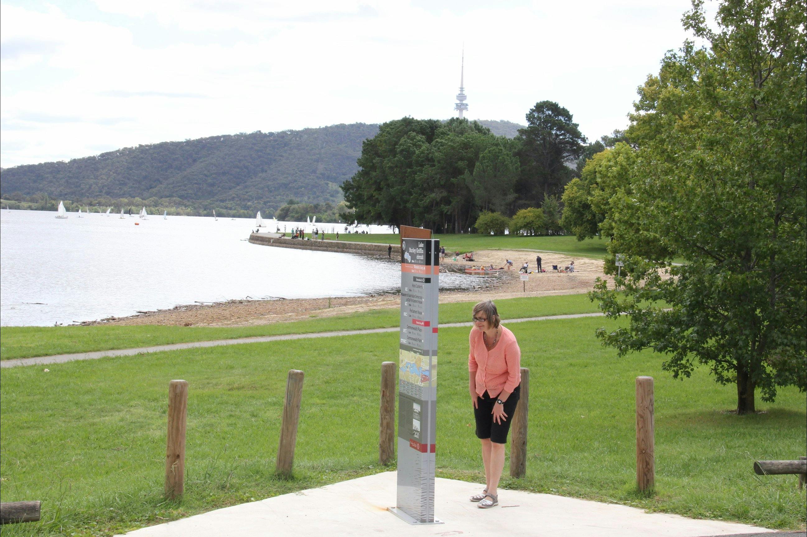 Woman looks at sign on lake edge