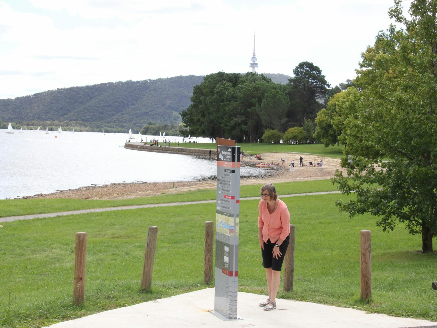 Woman looks at sign on lake edge