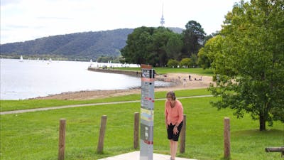 Woman looks at sign on lake edge