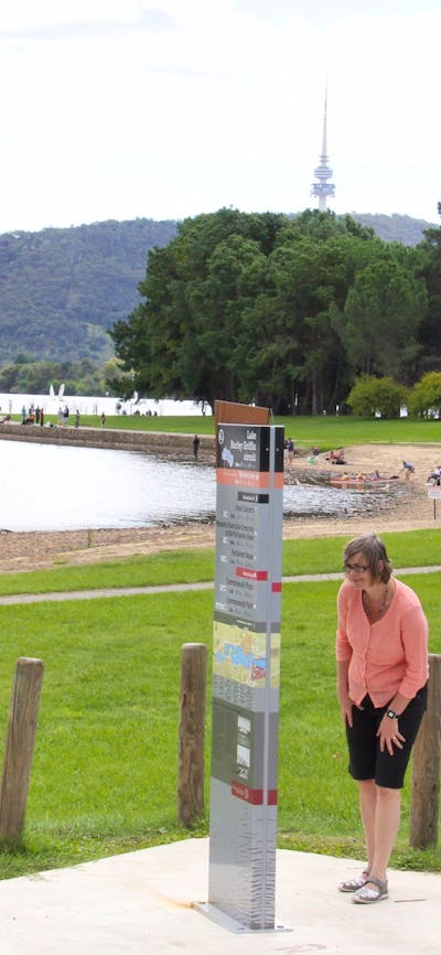 Woman looks at sign on lake edge
