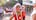 Two children dressed as elves happily wave at the camera, spreading holiday cheer.