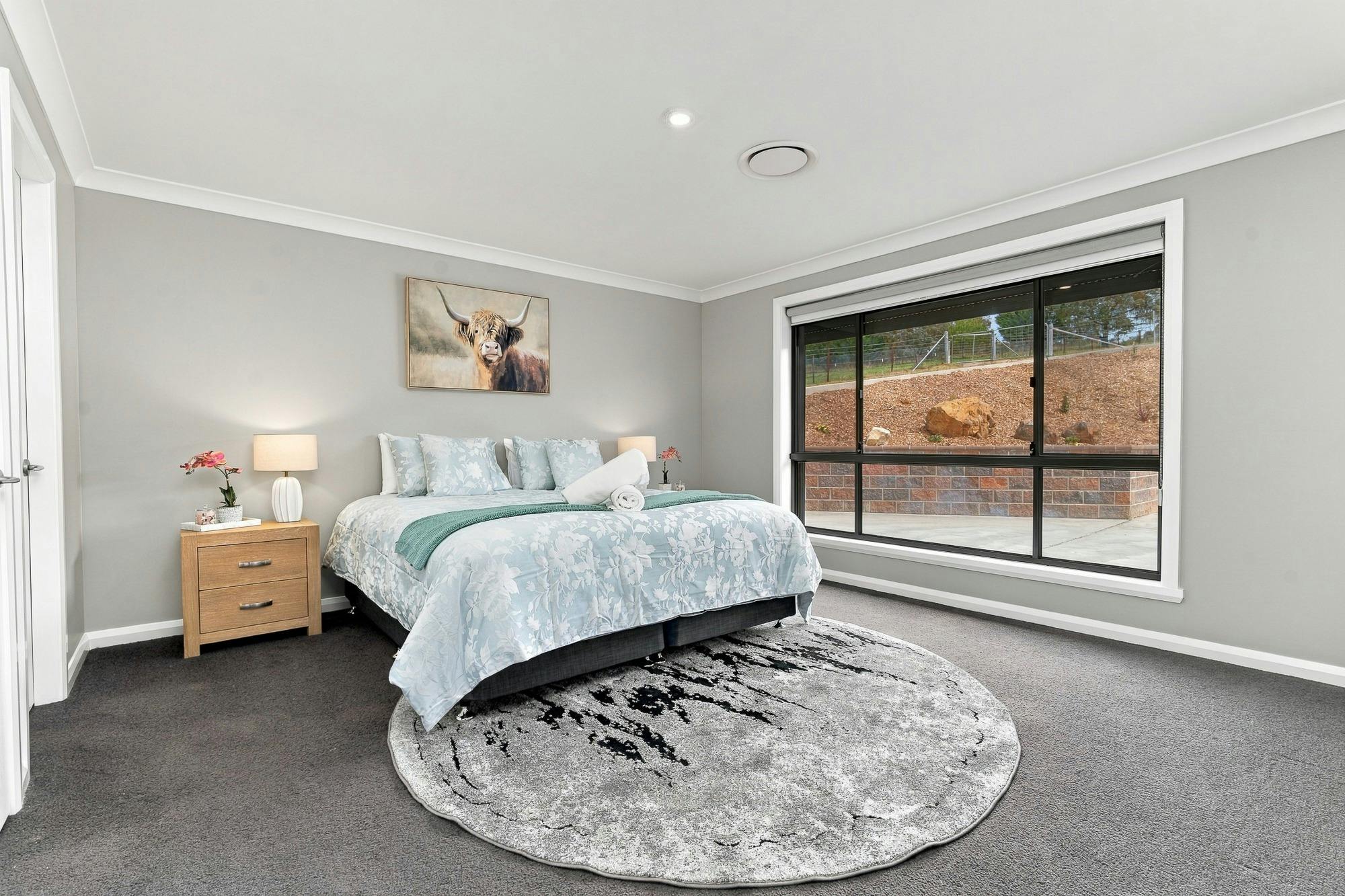 Main bedroom with large king bed, side tables and large window with a rug