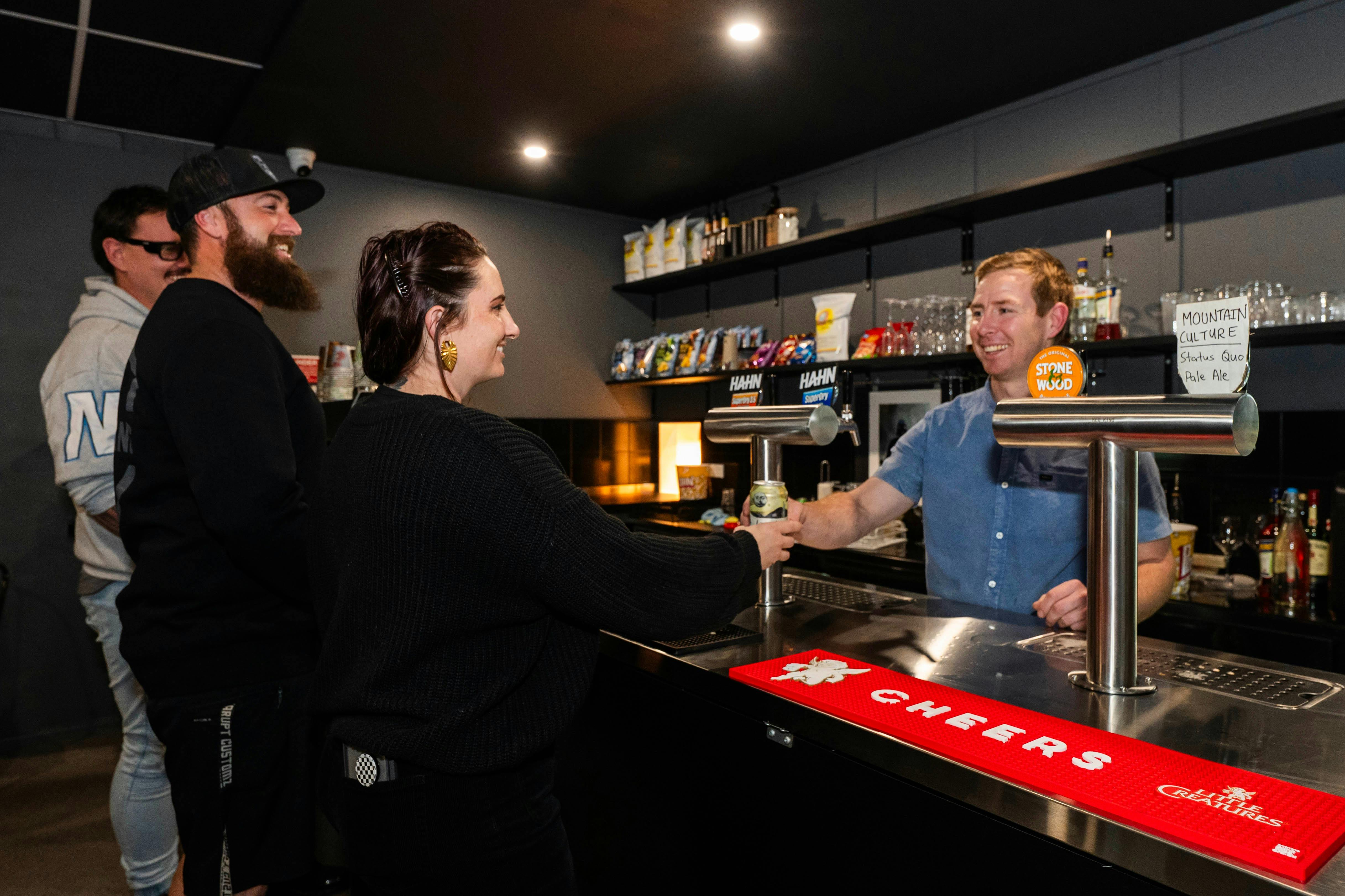 People standing at the bar inside Warp Arcade with drinks and neon lighting in the background