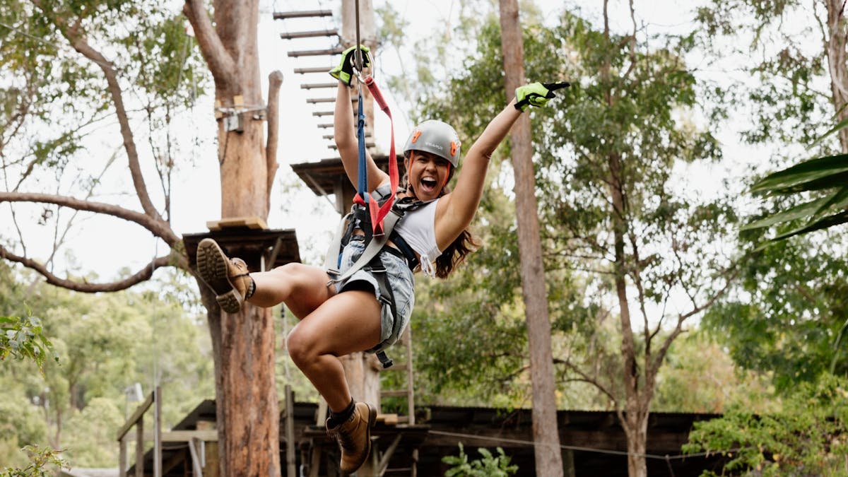 Woman ecstatic as she flies across a zipline.
