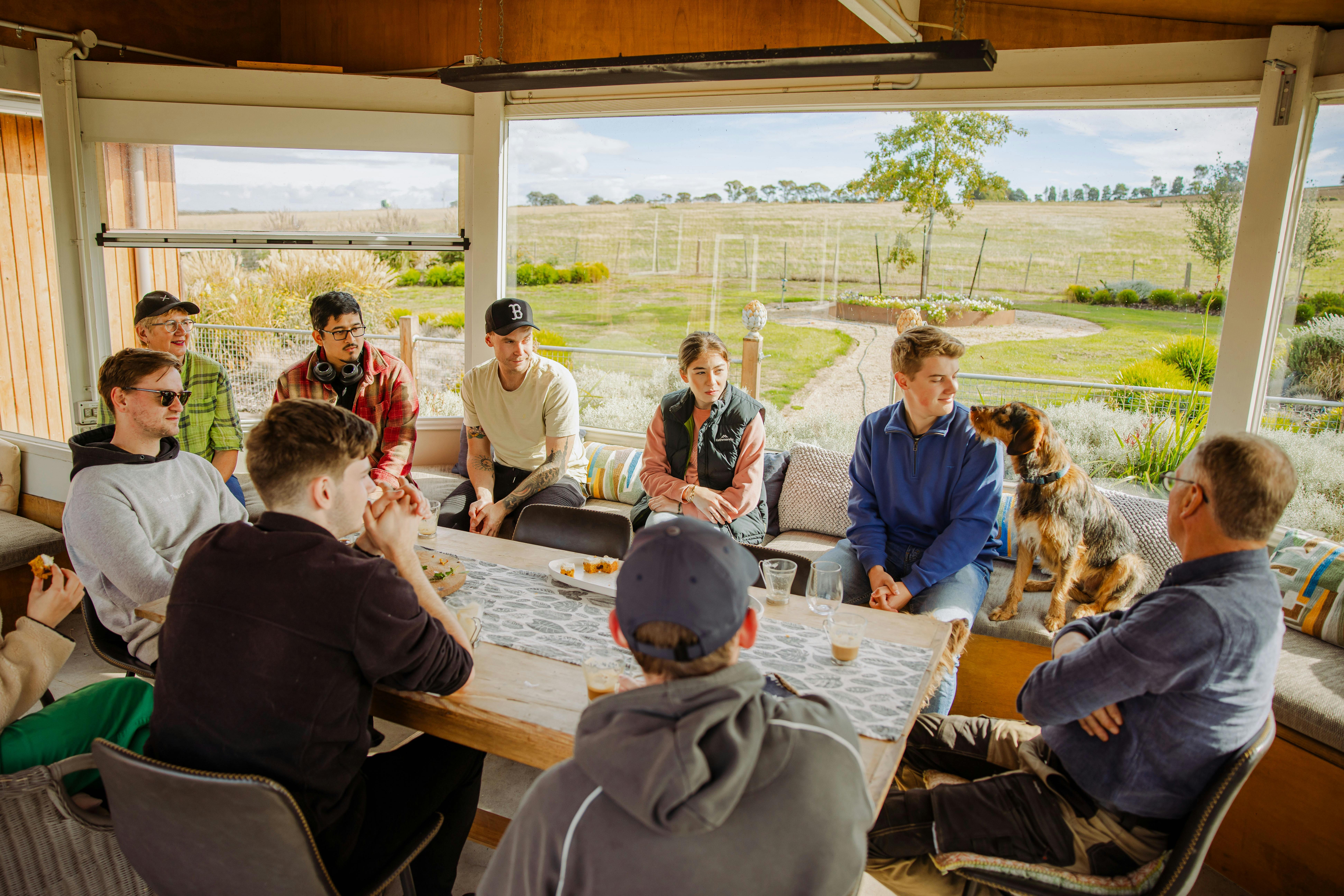 Guests seated at a long communal table at Mudbar Farm, open to the paddocks beyond.