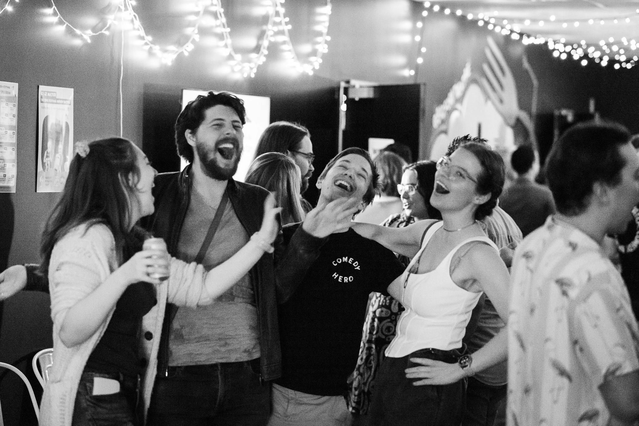 Black and White image of four audience members laughing in the bar