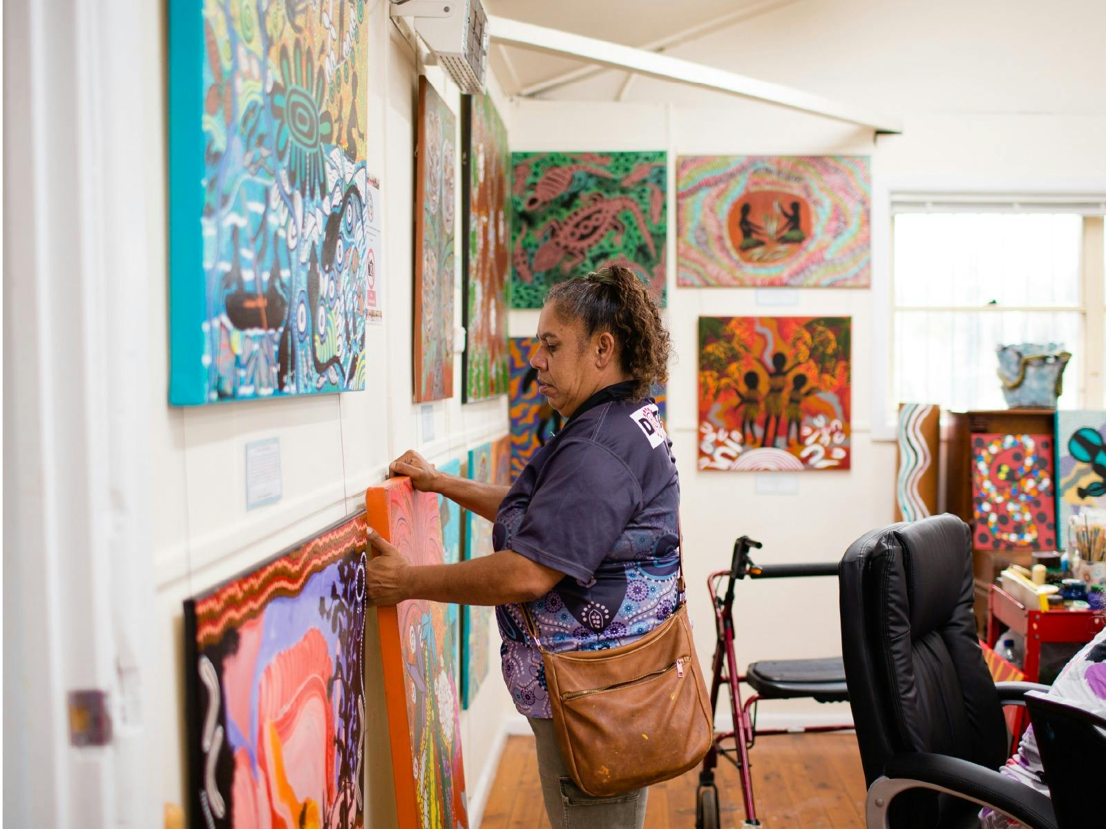 Side on photo of woman hanging artworks for exhibition