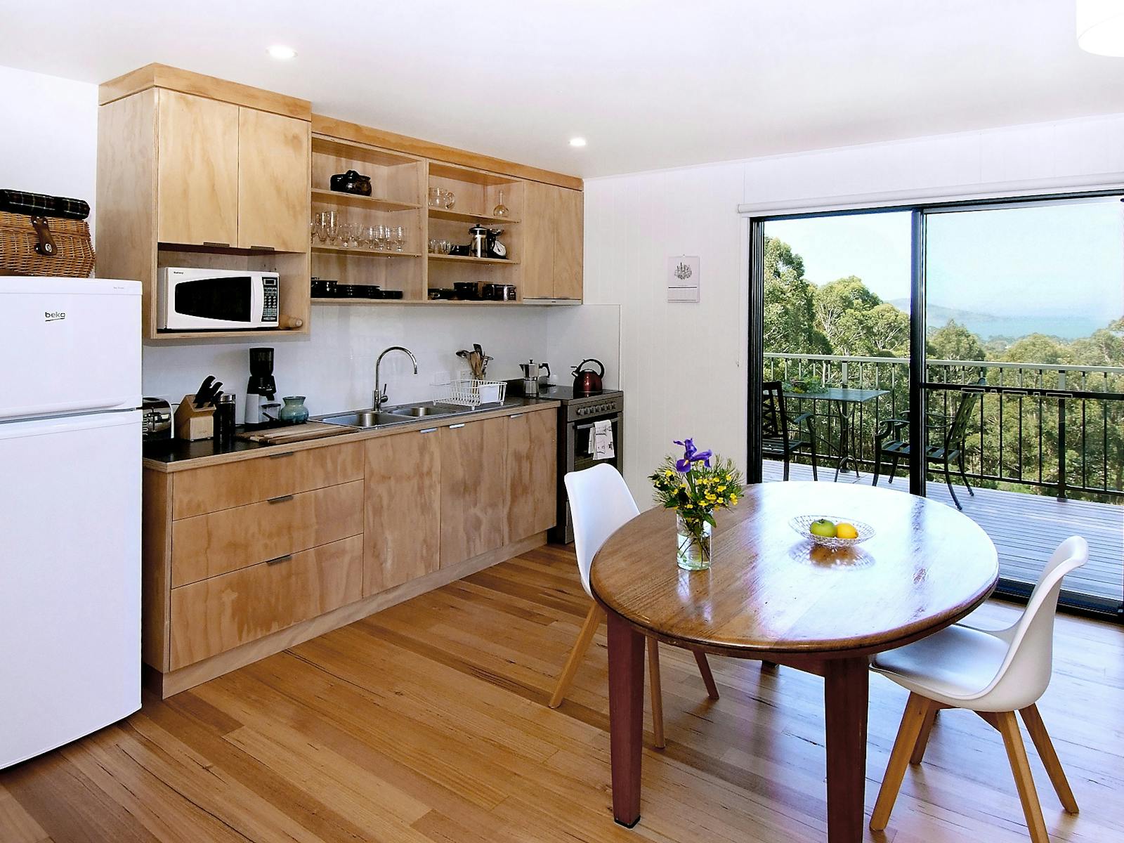 Dining table and chairs, kitchen showing sliding doors to deck and view