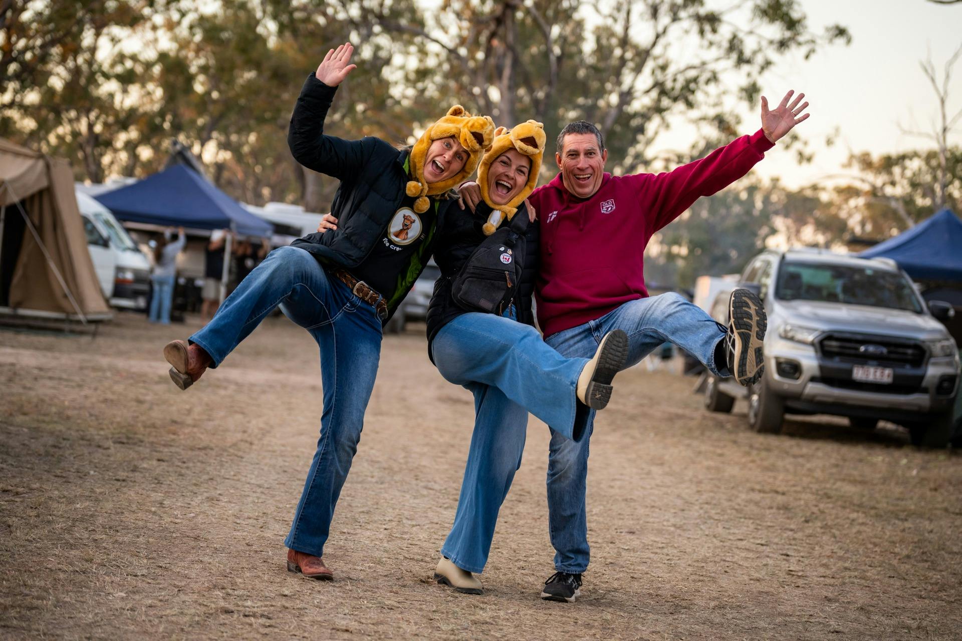Three people with camel hats in front of campsite