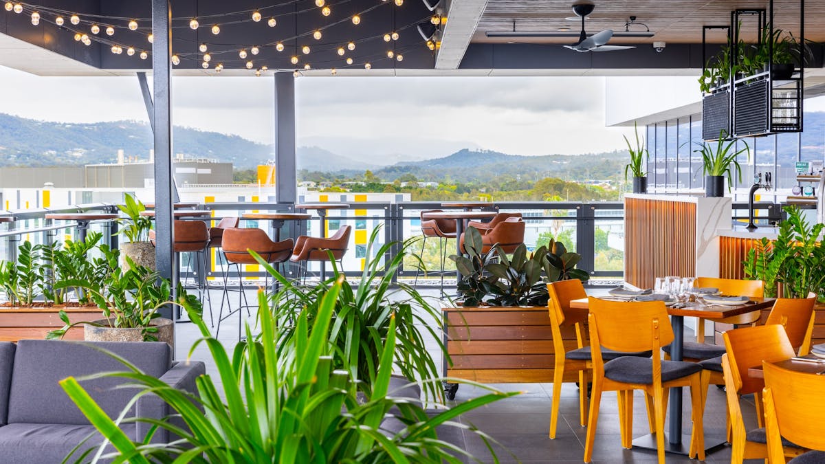 Rooftop area with lounges and tables, festoon lights and hinterland views