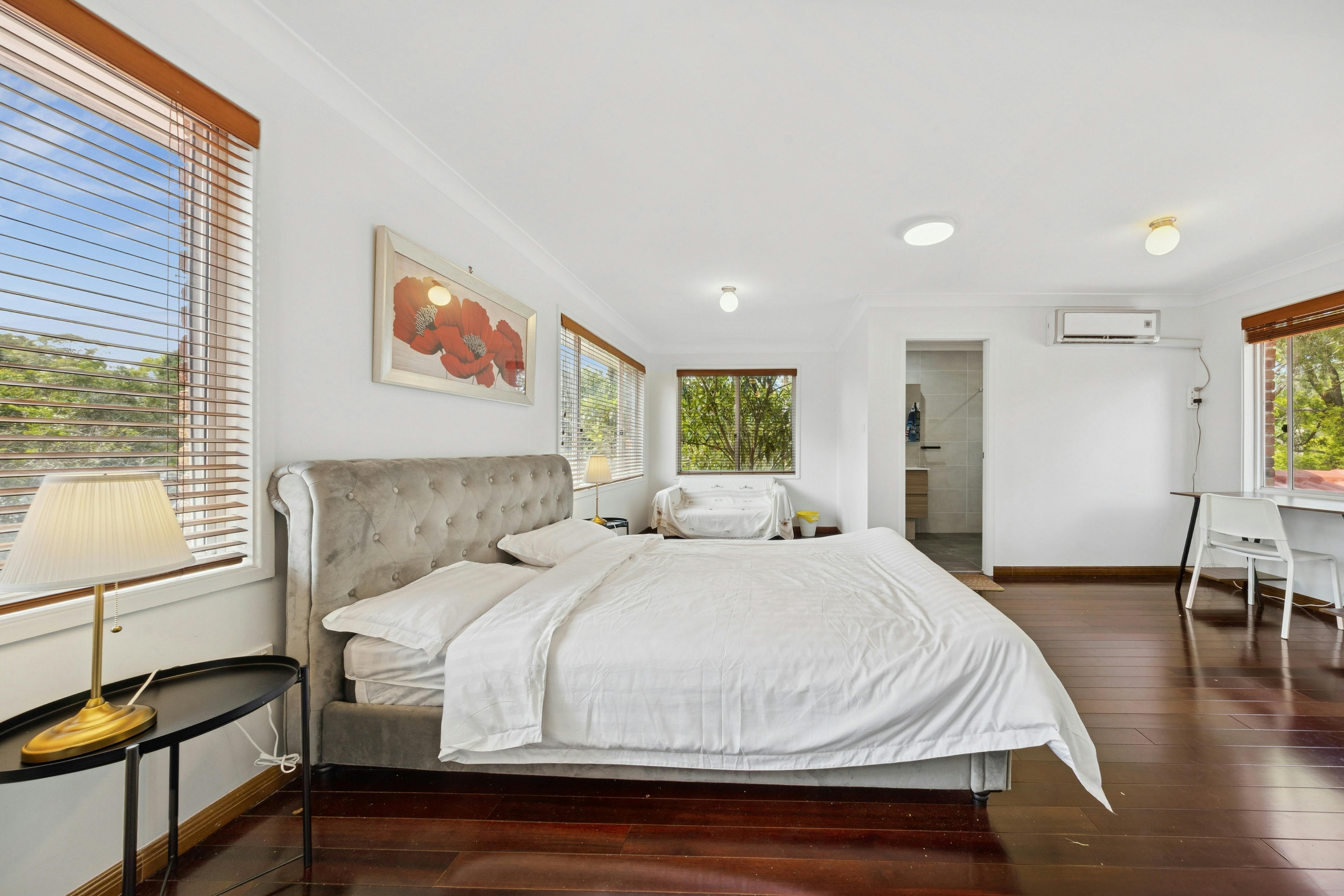 bedroom view showcasing the queen-sized bed, bedside table, and natural light from the windows.