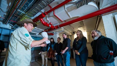 Man in khaki clothing talking to a group of people