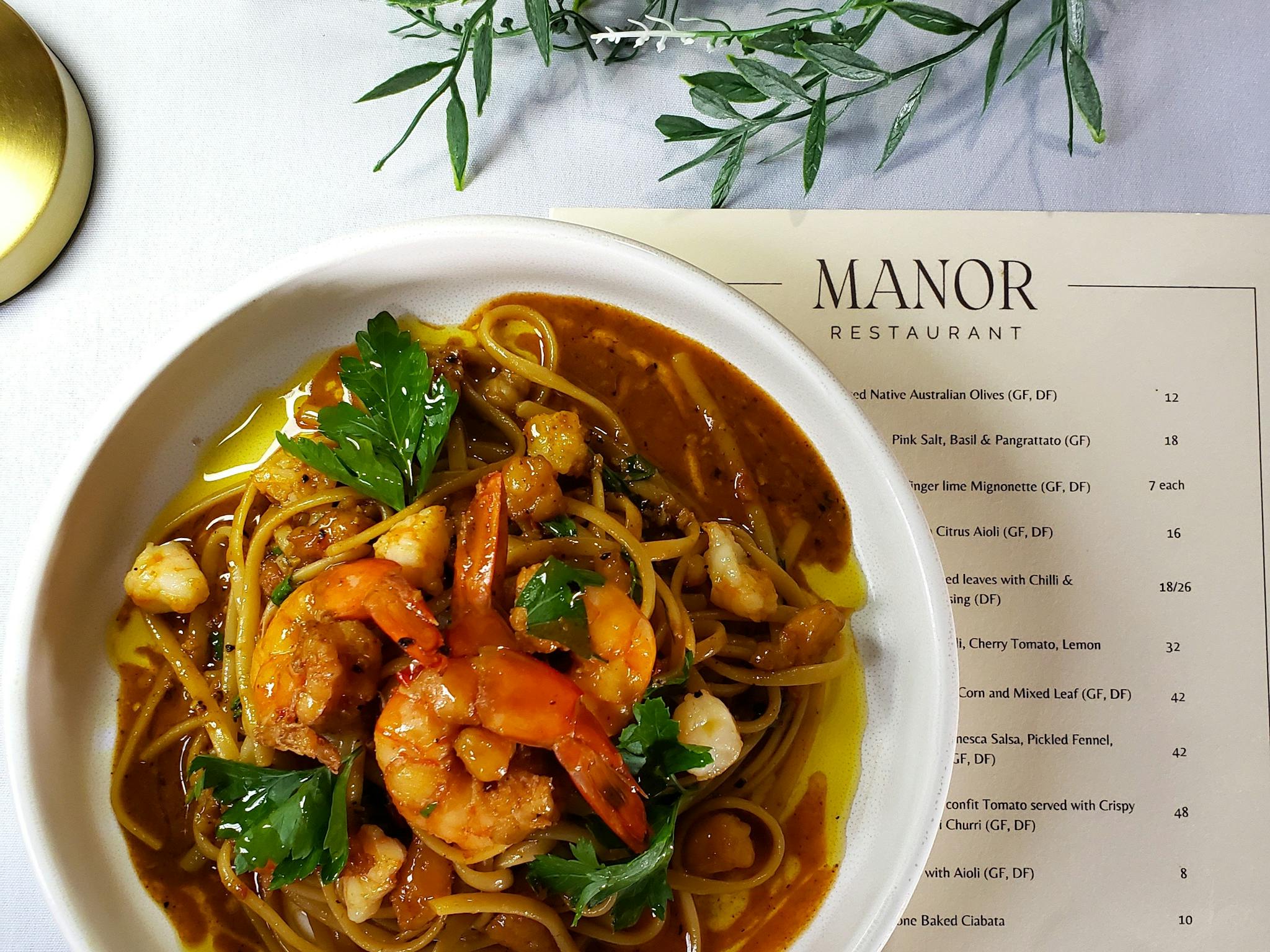 Image of a seafood pasta dish on a table with a menu beside it