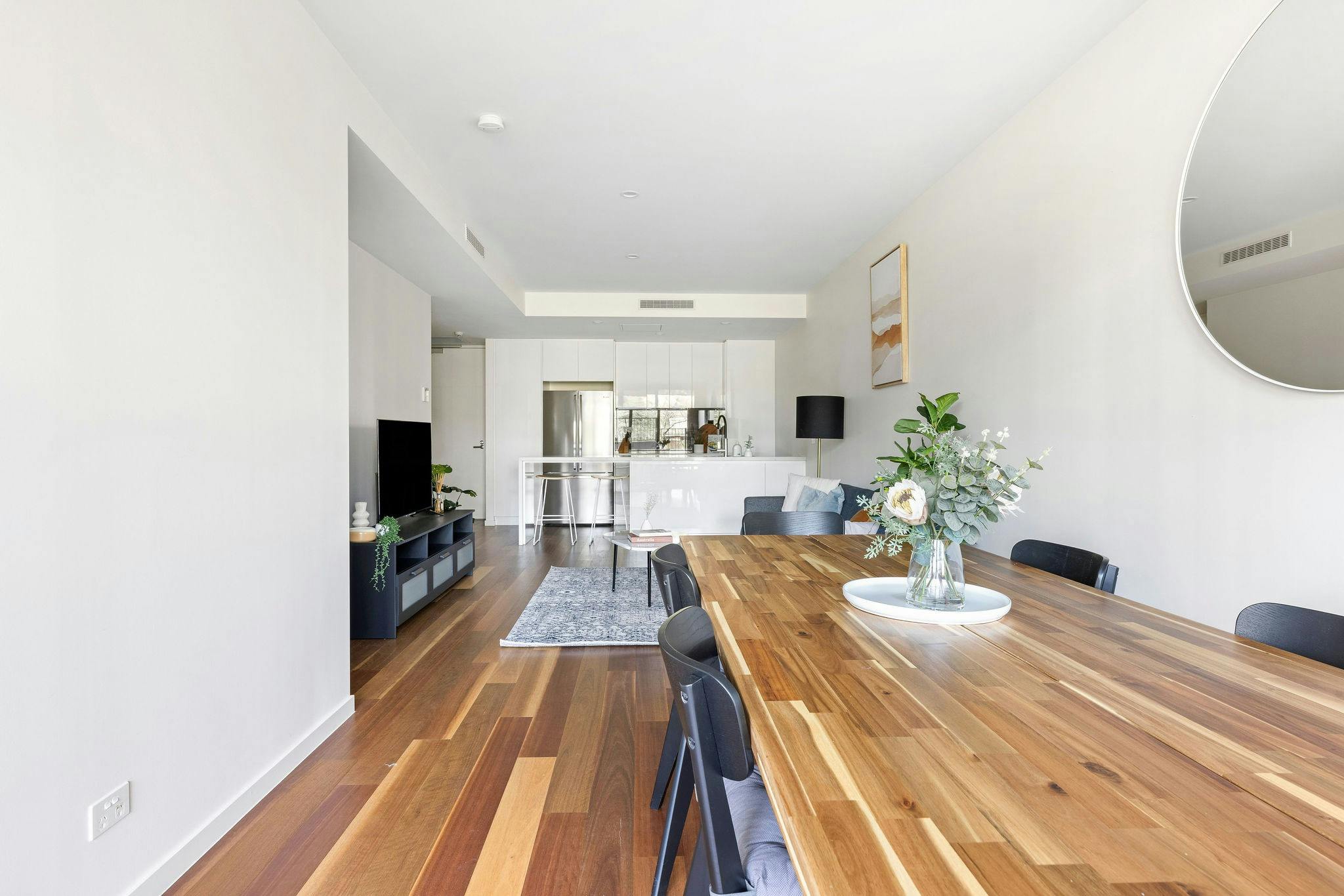 Large spacious dining area with large dining table, wood-look floors and modern kitchen.