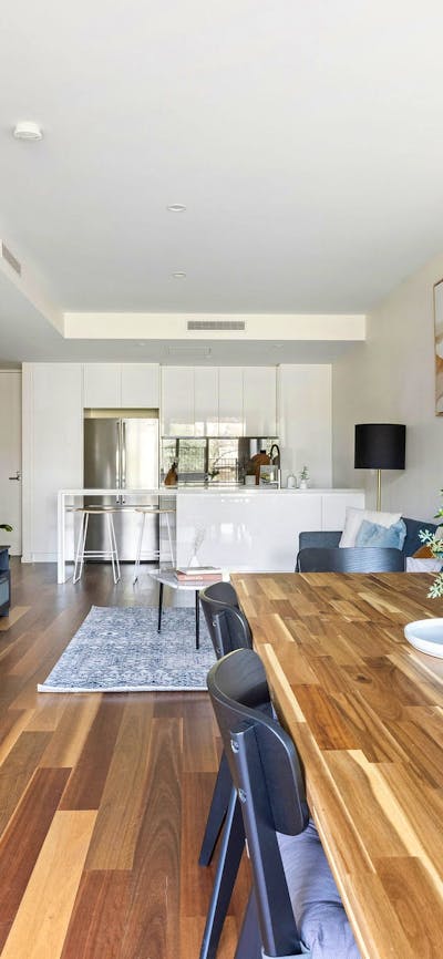 Large spacious dining area with large dining table, wood-look floors and modern kitchen.