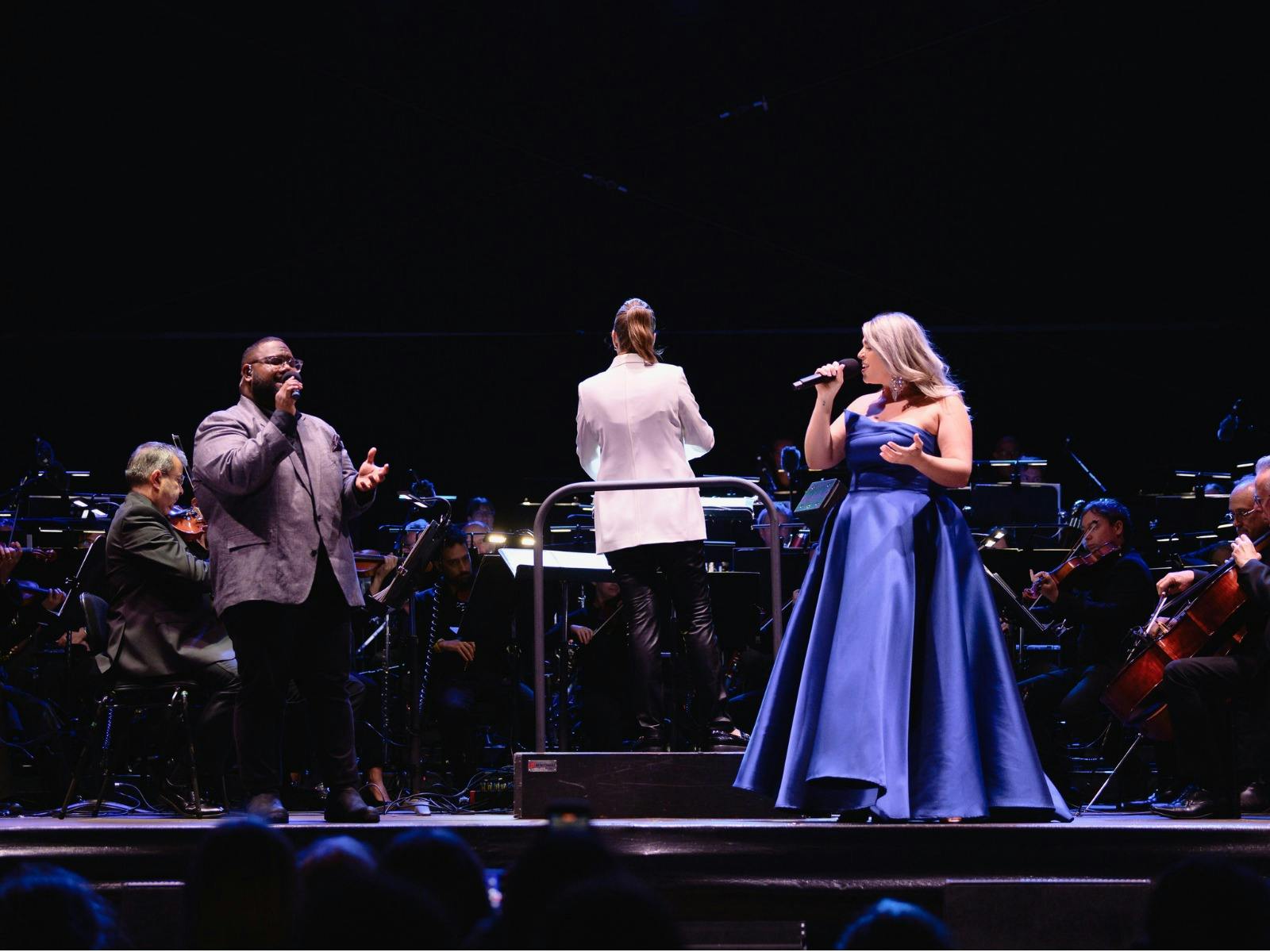 Woman in a blue dress standing on stage and singing