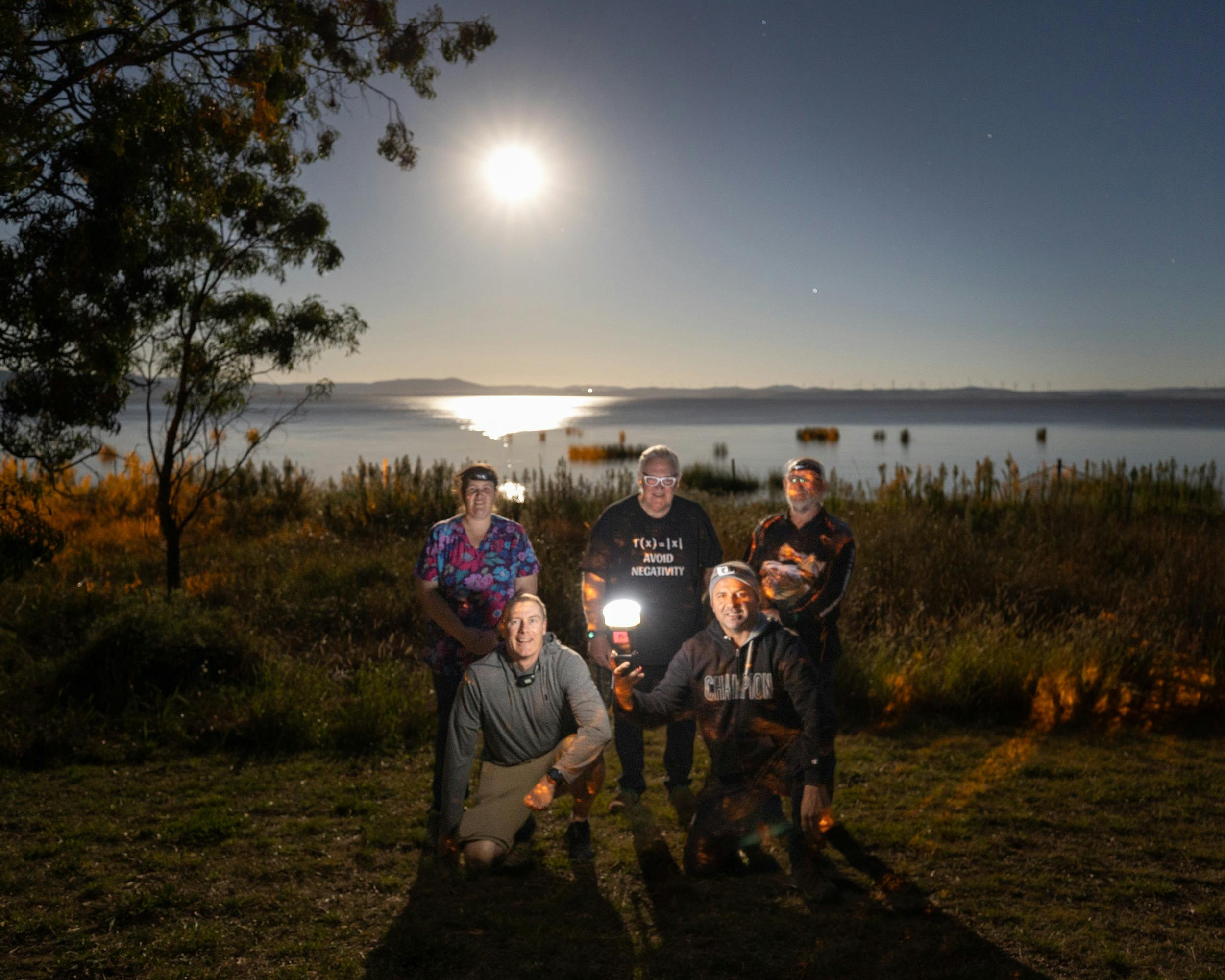 A portrait of a group of participants with Moon reflecting over a lake