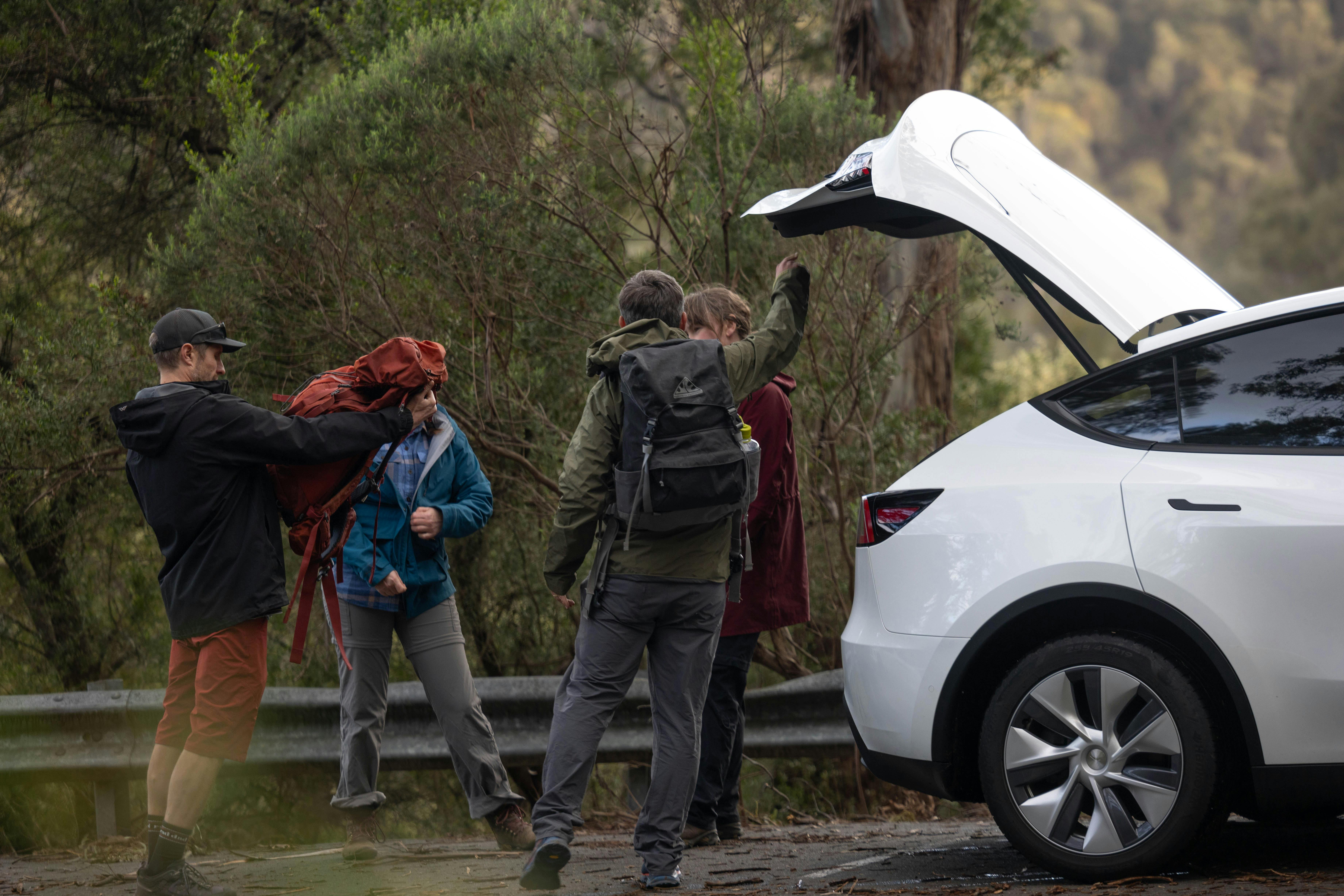 Friends unloading gear from an Electric Vehicle hire car (Tesla Model Y), ready to commence hiking.