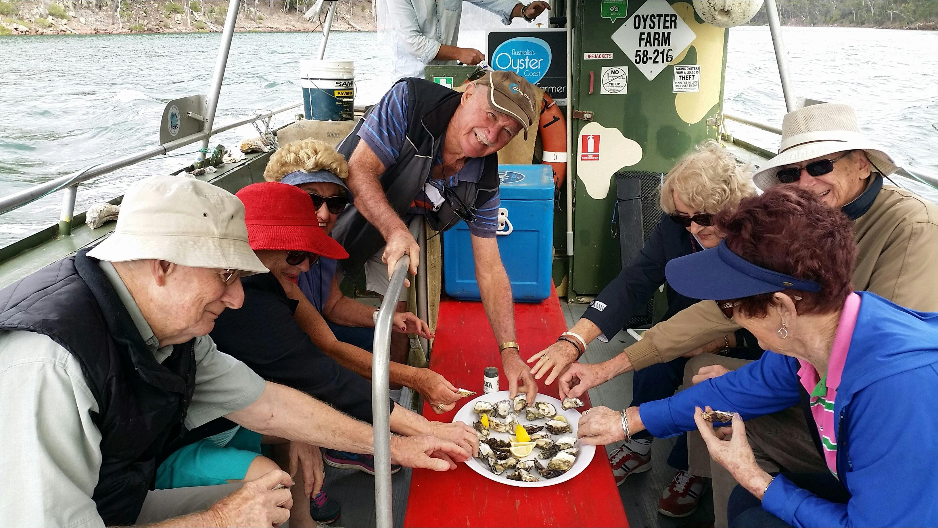 several people reaching for plate of oysters on oyster punt