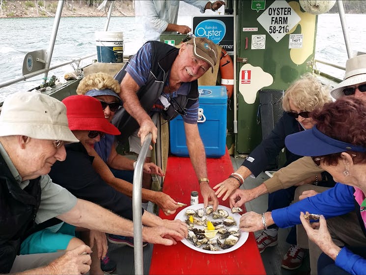 several people reaching for plate of oysters on oyster punt