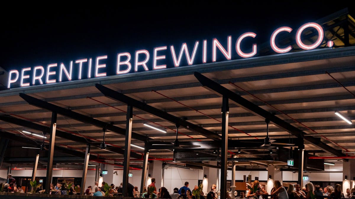 Night time outdoor shot of the Perentie Brewing Co sign and people dining