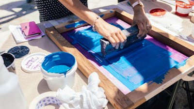 Two women hold a screen flat and squeegee