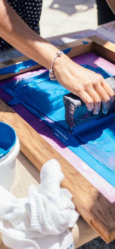 Two women hold a screen flat and squeegee