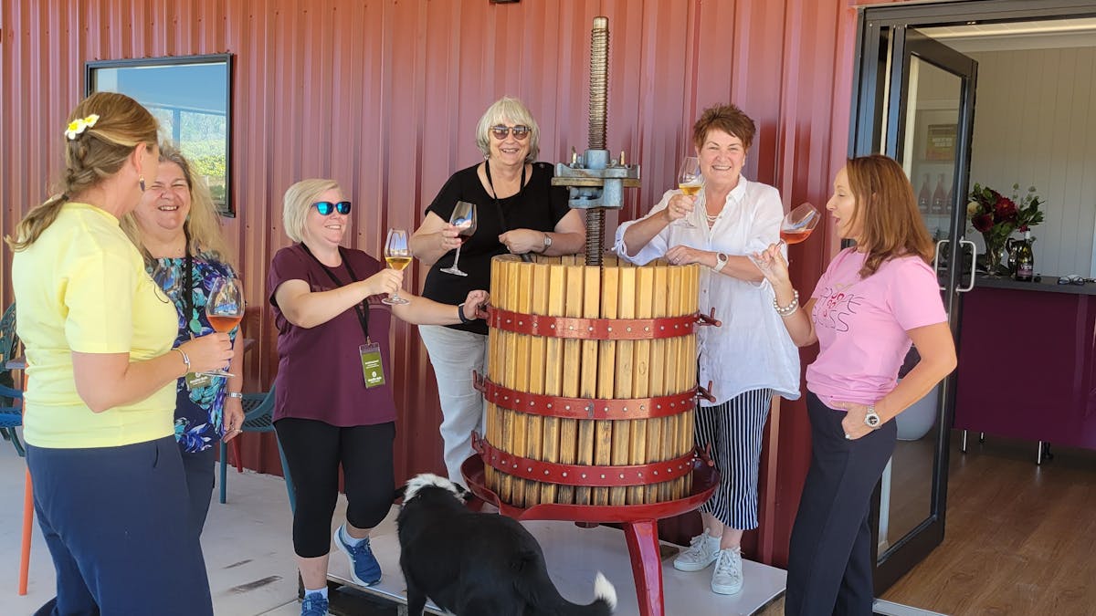 Ladies drinking wine around the wine press at Grape to Glass experience, View Wine - Ballandean