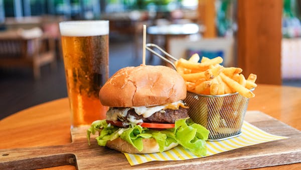 An image featuring a burger, chips & beverage