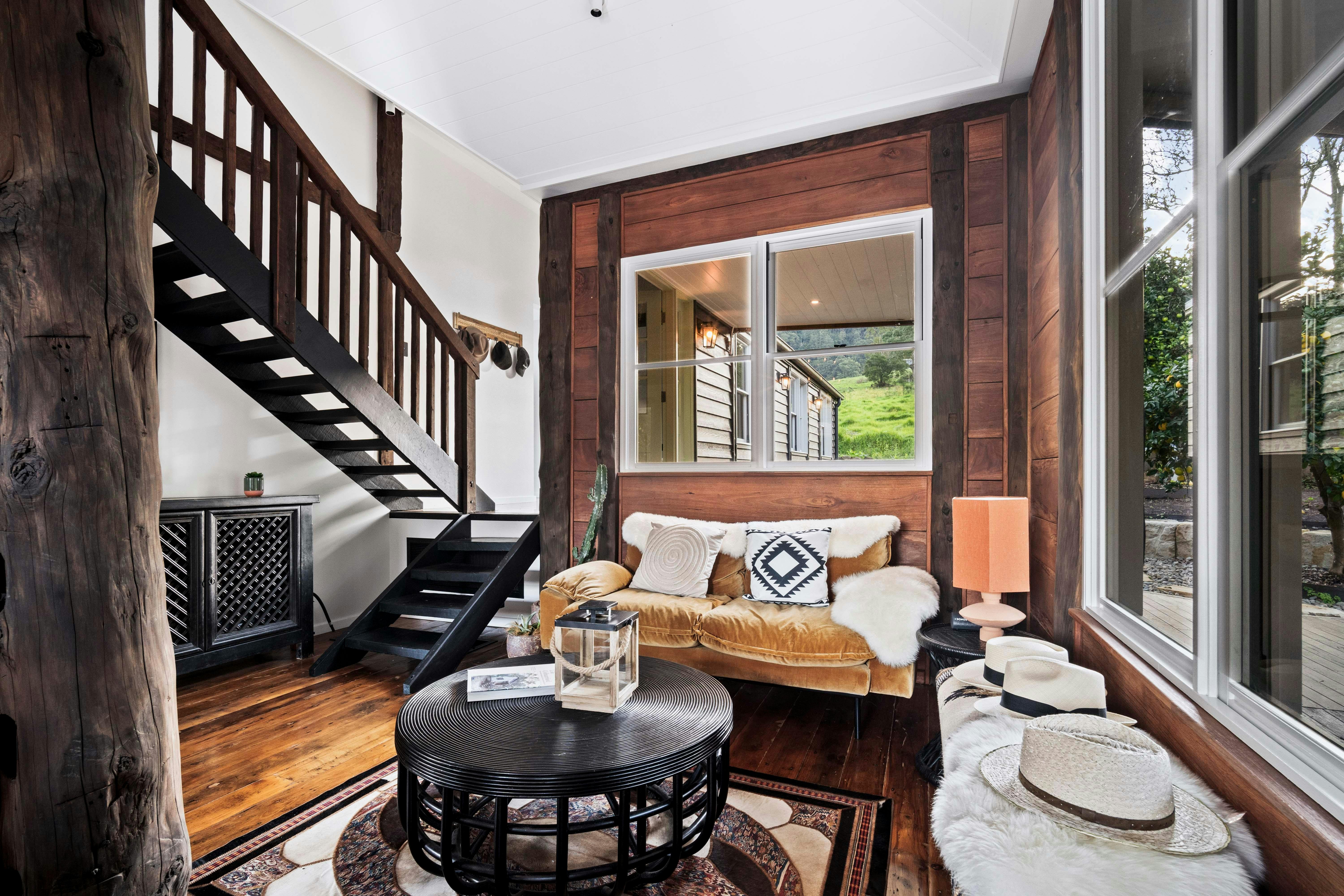 An image of a lounge room with eclectic furniture, sheep skins and timber panelled walls