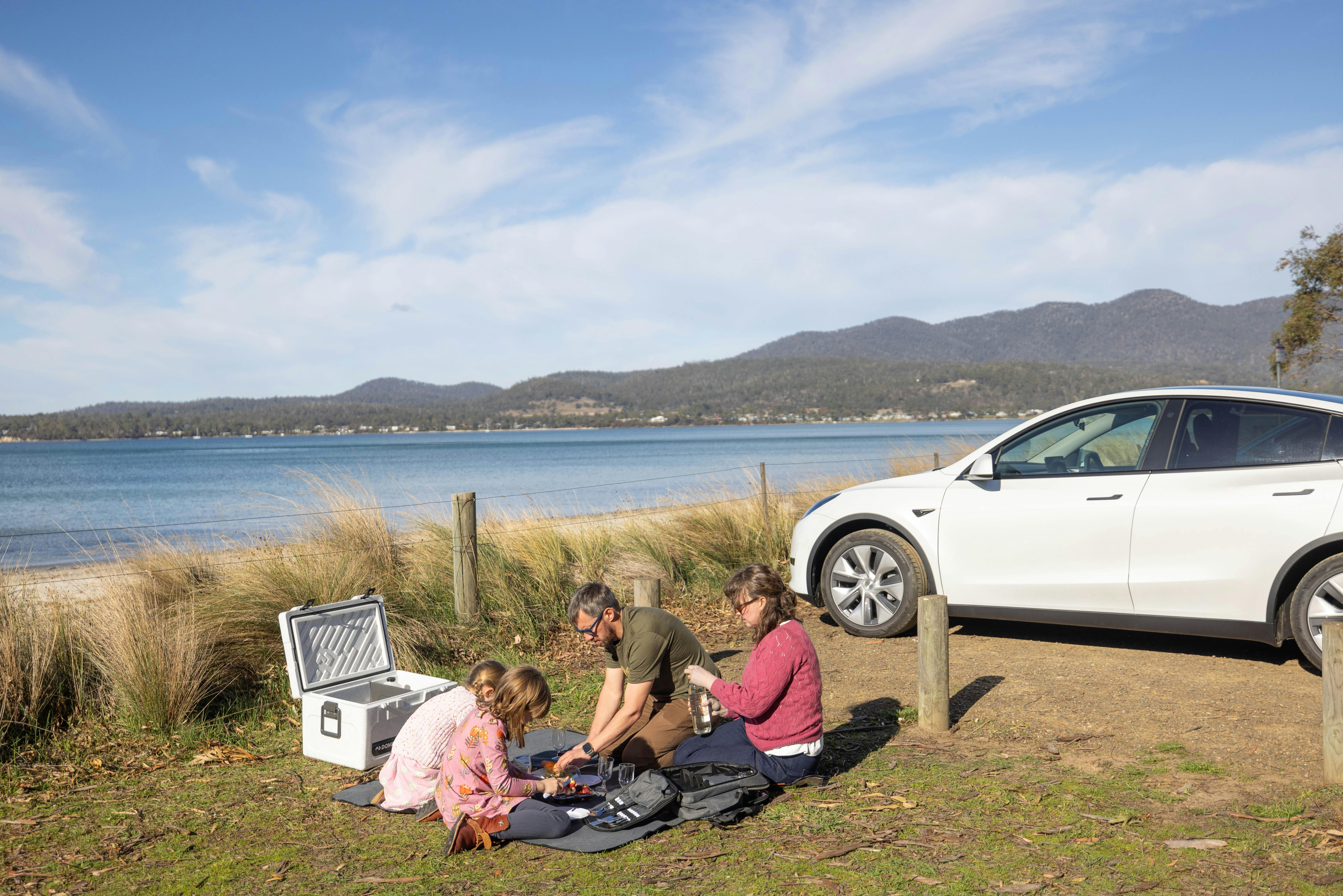 Tourists enjoying complimentary picnic equipment included with Electric Vehicle hire car in Tasmania