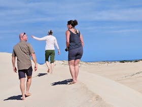 Coonawarra Experiences guests walking barefoot across coastal sand dunes under a clear blue sky