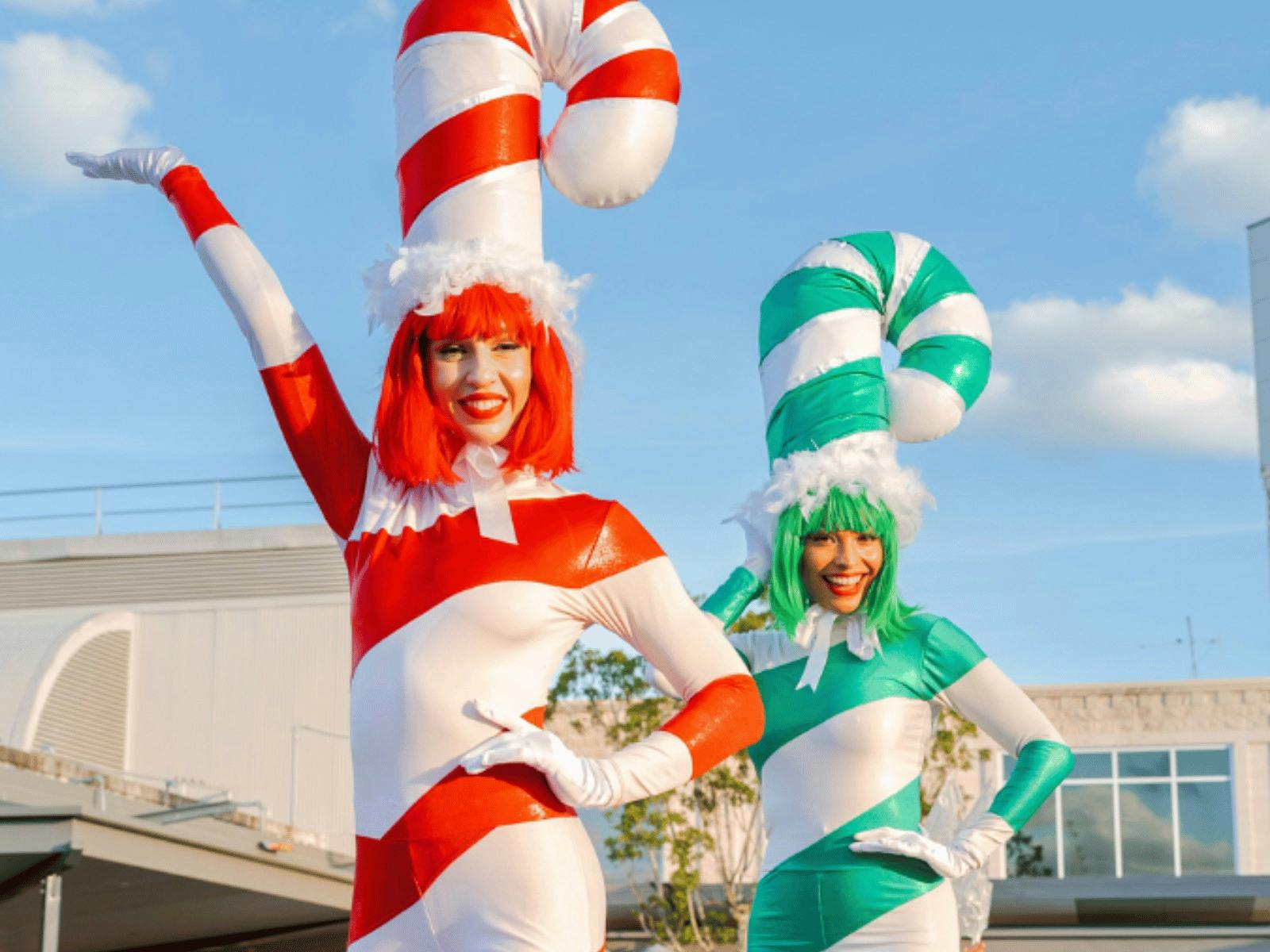 Two candy cane stilt walkers waving at the camera at the Sunshine Plaza