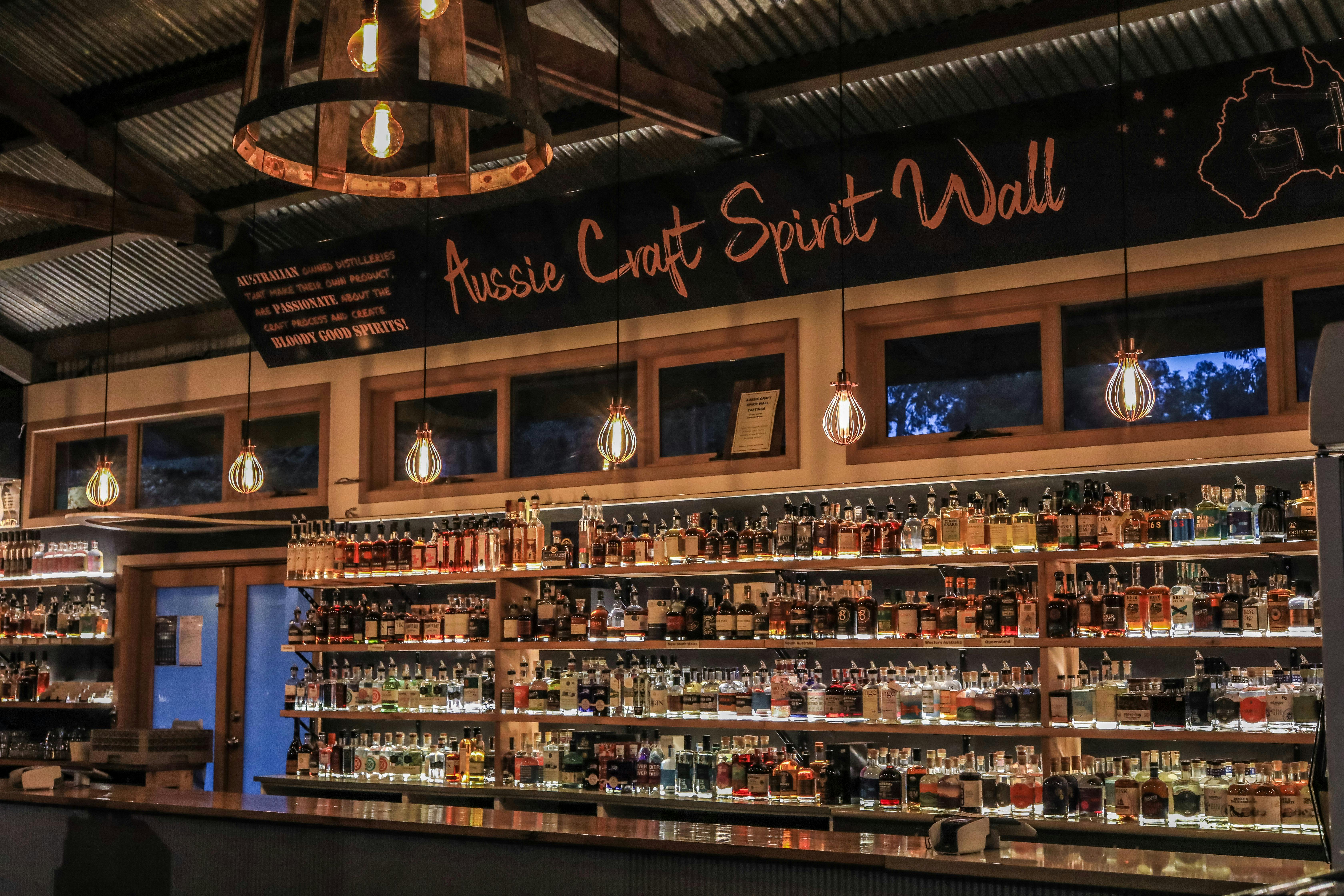 A bar wall full of bottles of spirits - a banner above read "Aussie Craft Spirit Wall"