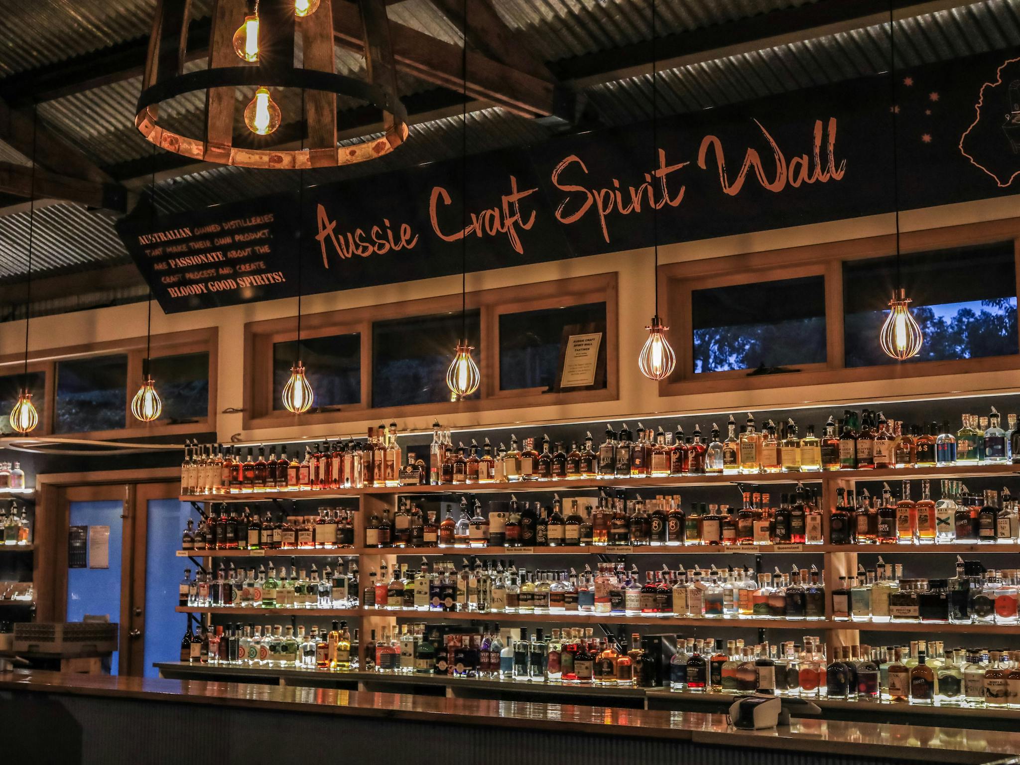A bar wall full of bottles of spirits - a banner above read "Aussie Craft Spirit Wall"