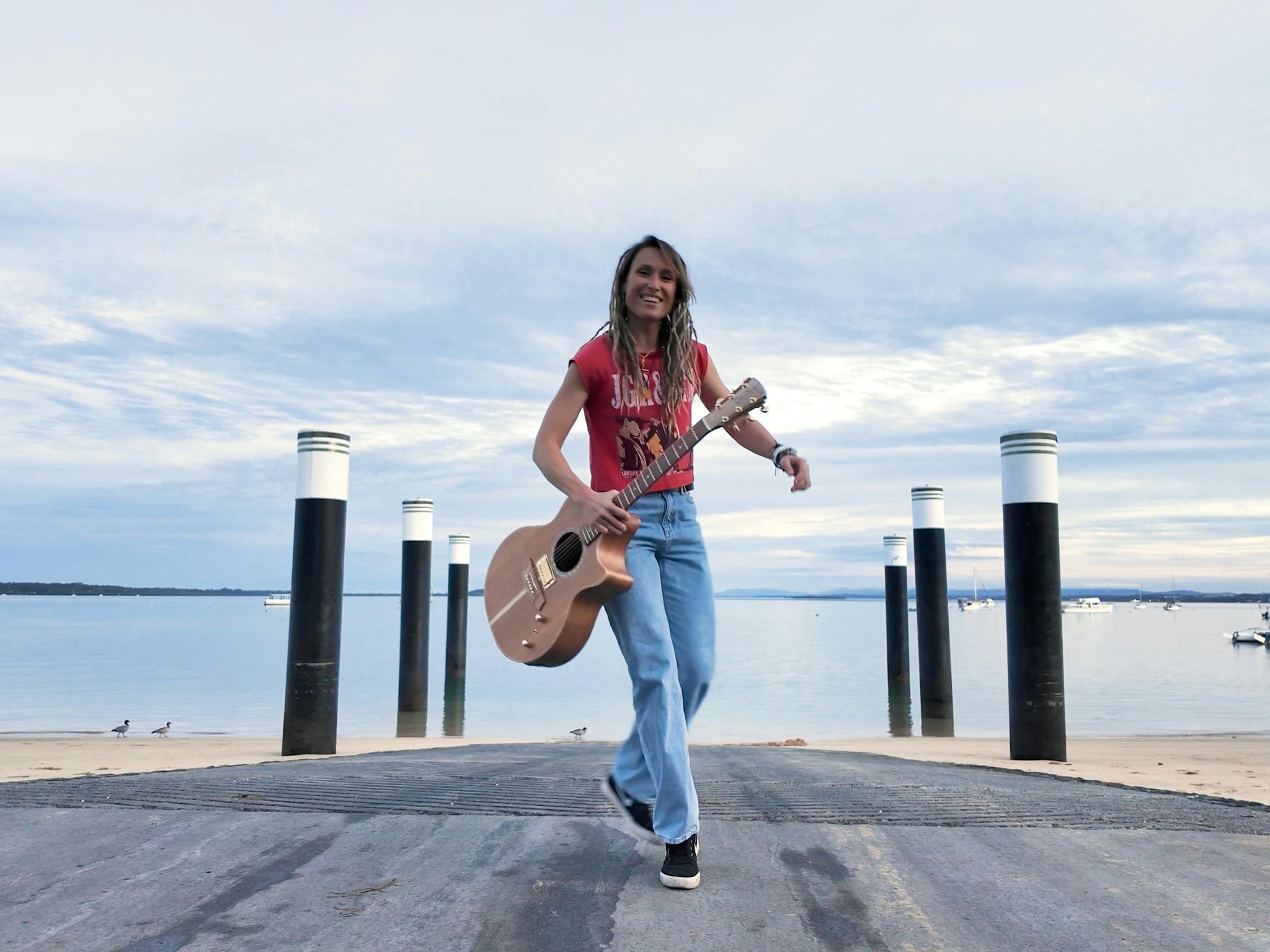 Majelen holding her signature Cole Clark guitar on the jetty at Coochiemudlo Island