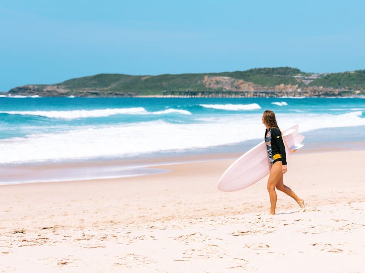 Girl entering the surf at with Catherine Hill Bay jetty in background