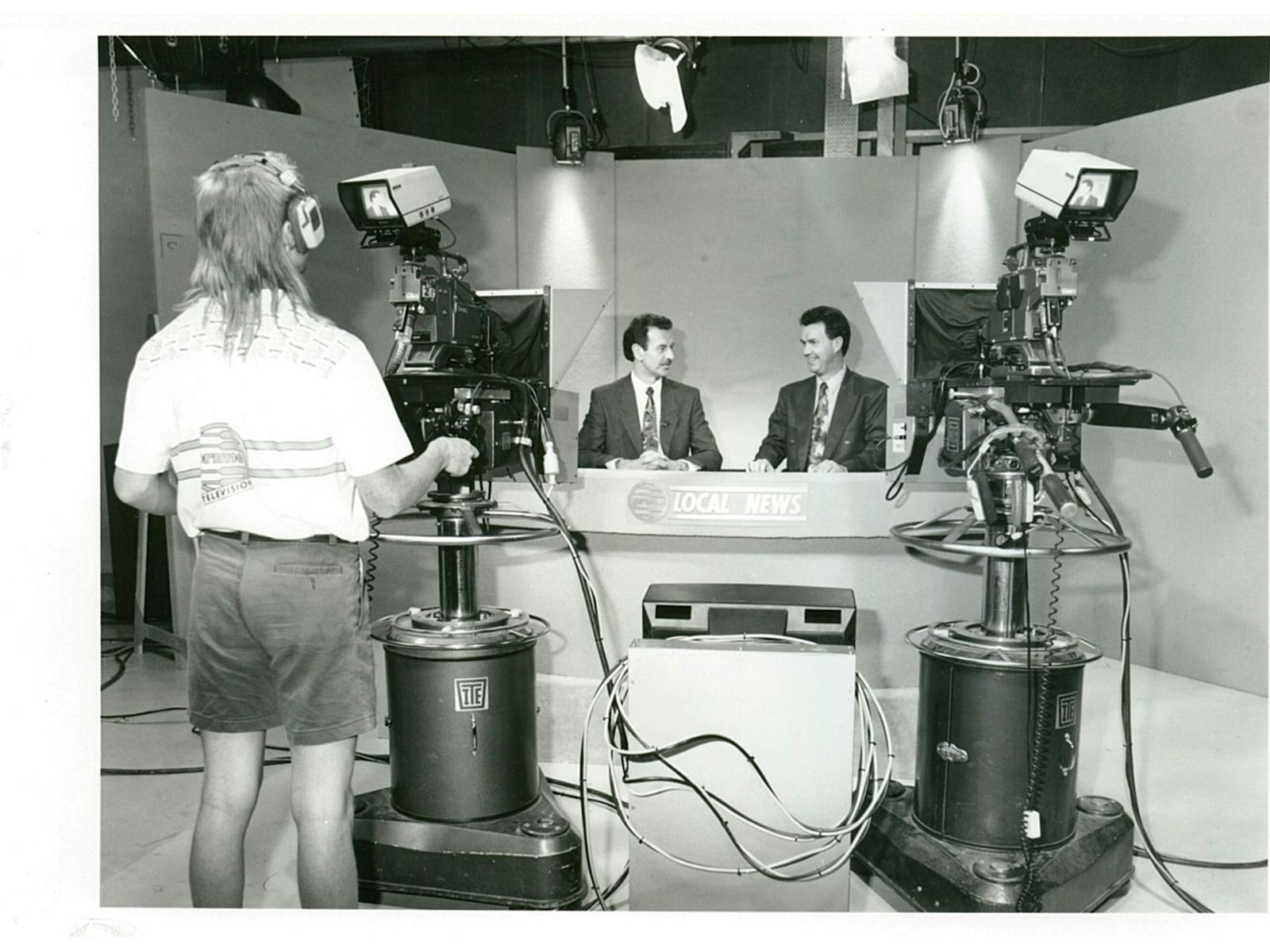 Two newsmen and a cameraman in a television studio.