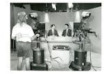 Two newsmen and a cameraman in a television studio.