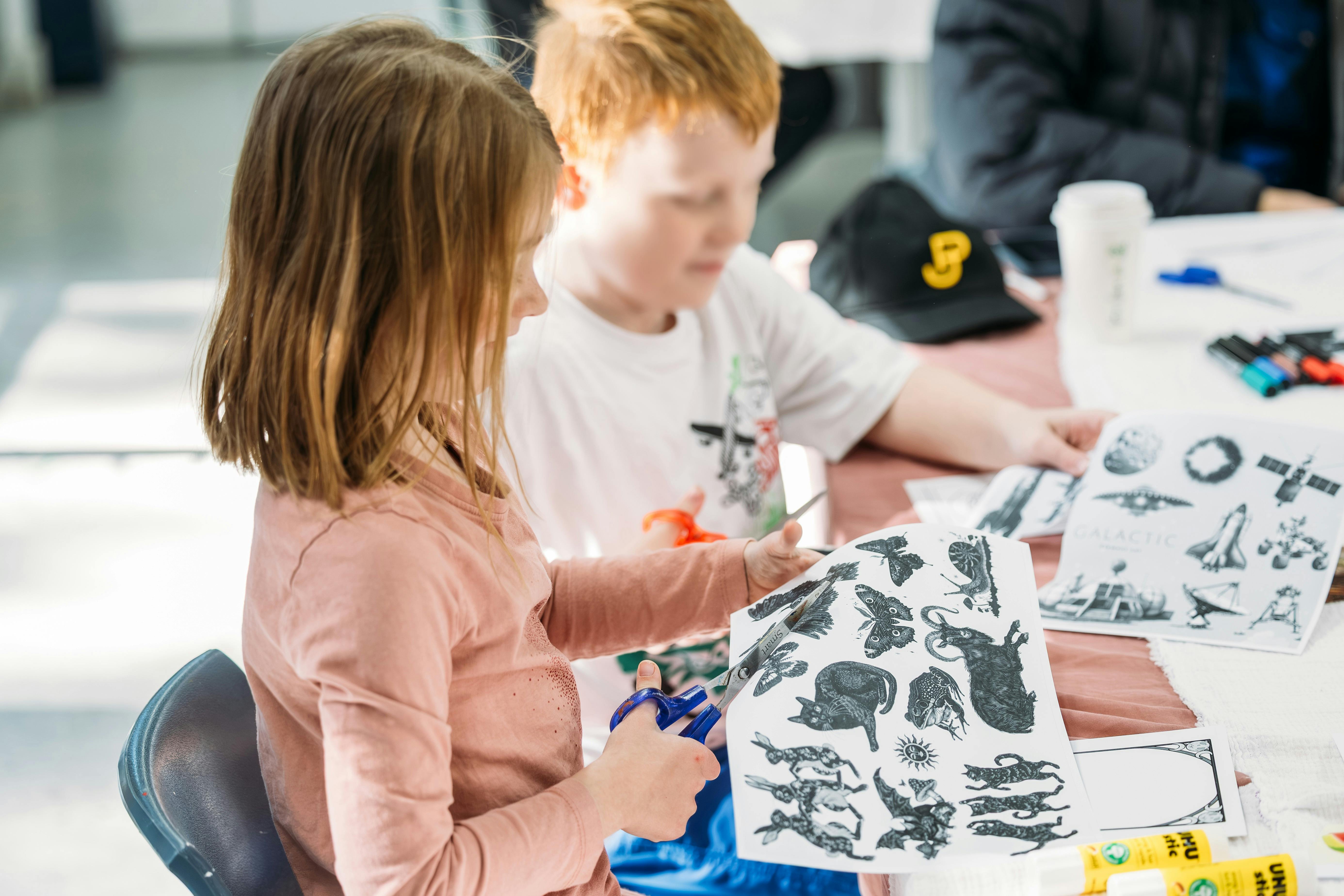 Two children sit at a table during an art activity.